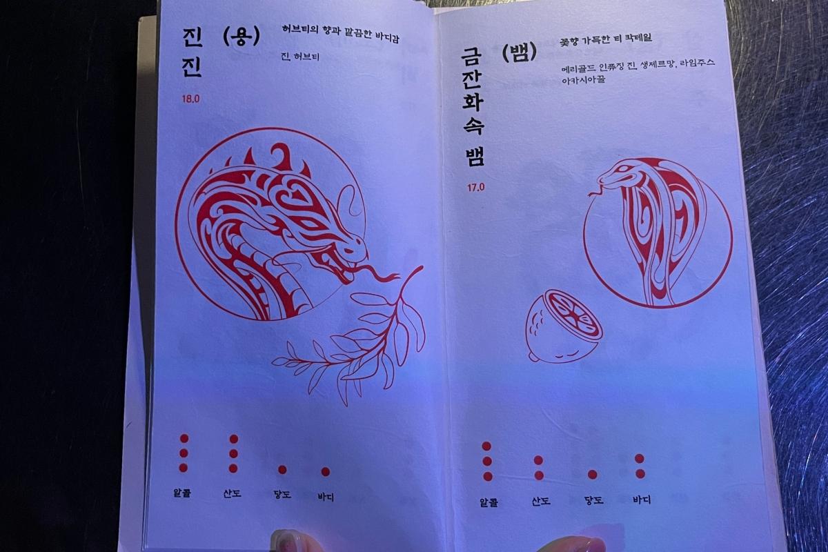 Меню коктейлей зодиакальной тематики в Zoo Sindang, Сеул, представляющее дракона и змею в художественном оформлении.