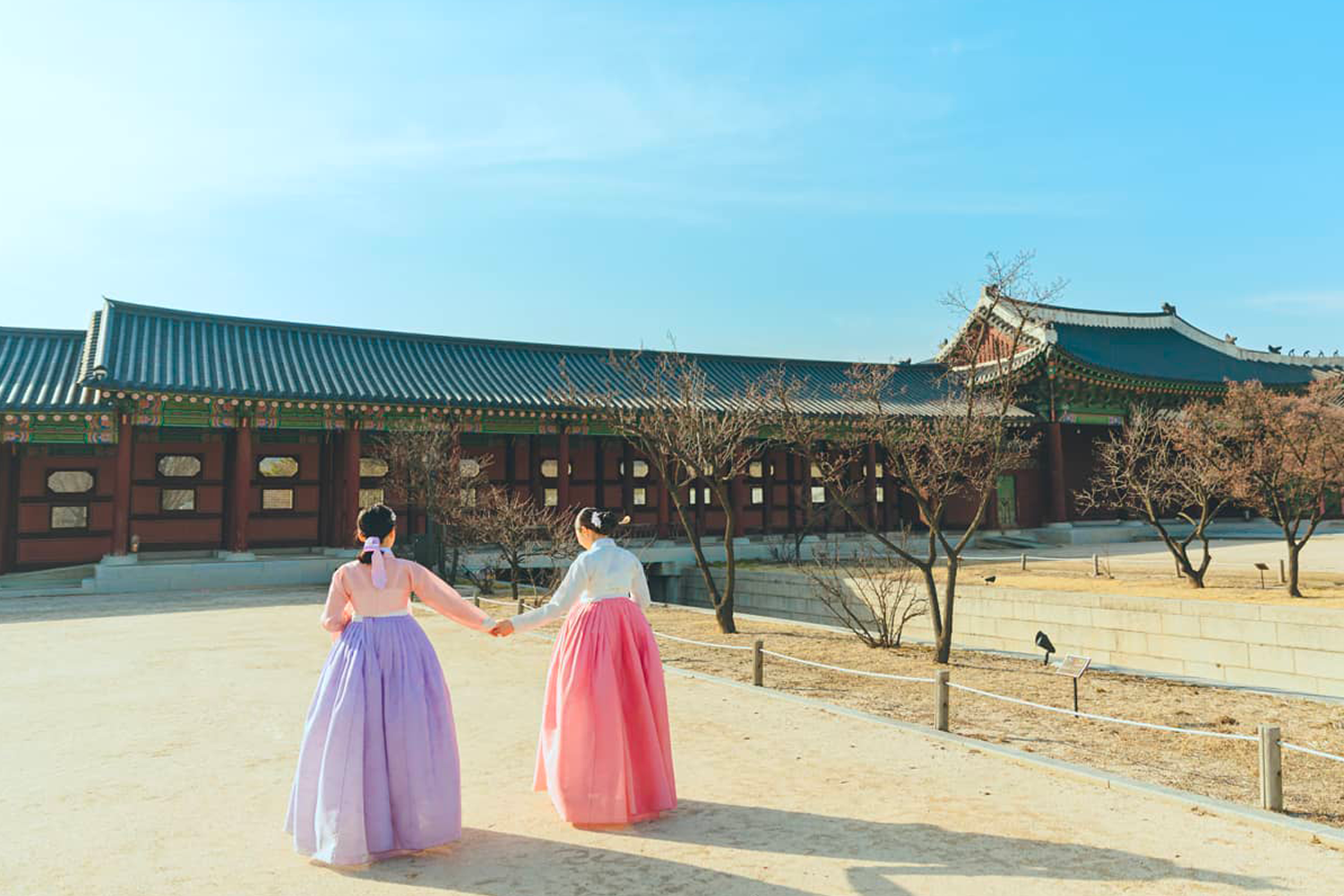 古色古香的景福宮背景中，兩人身著傳統韓服行走，展現出悠閒的韓式傳統美學，是文化與時尚融合的典範。