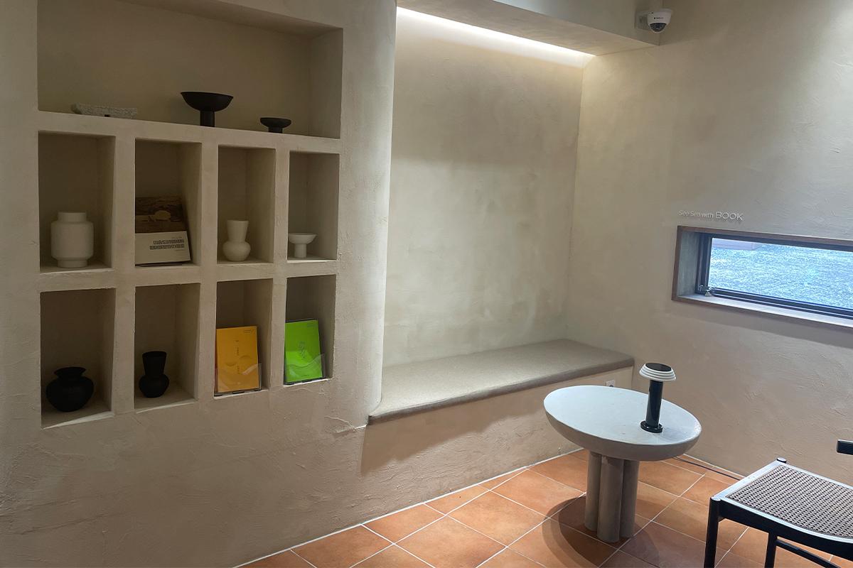 Внутренний вид книжного кафе Sea Sea with Book, акцент на минималистский дизайн интерьера и полки.