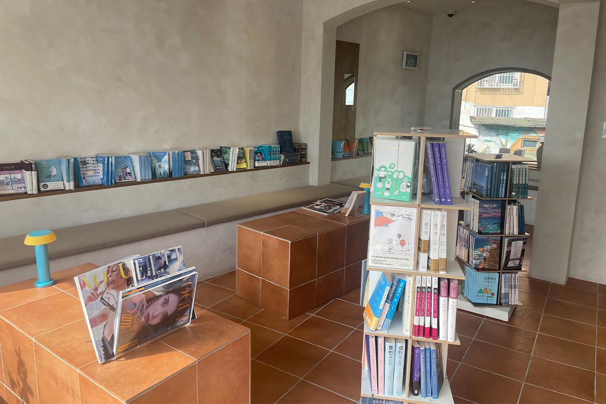 Интерьер книжного кафе Sea Sea with Book с выставкой книг и минималистским дизайном.