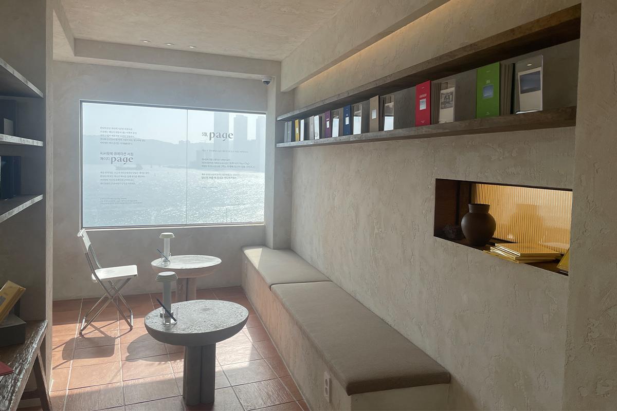 Столики и стулья у окна с видом на океан в книжном кафе Sea Sea with Book.