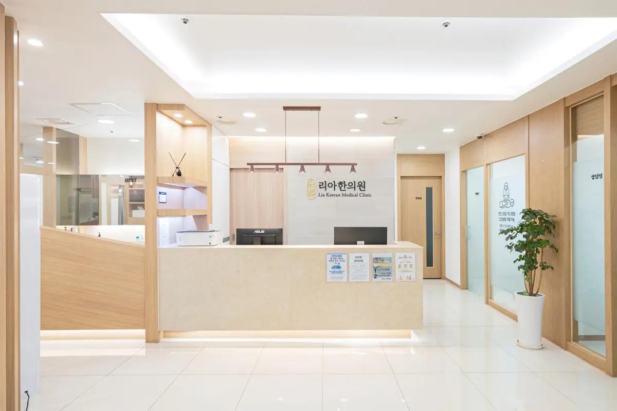 診療所の受付エリアの写真。白と木製のシンプルで清潔な内装が特徴で、リア韓医院のロゴが正面にある。