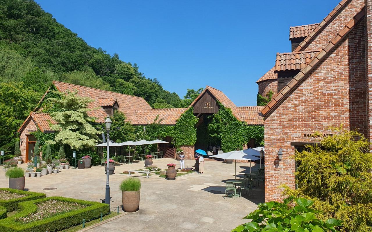Jade Garden arboretum entrance in Gangwon Province, surrounded by lush greenery and ivy-covered brick buildings.
