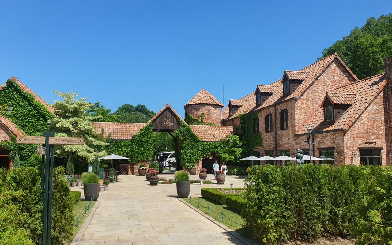Scenic view of Jade Garden's courtyard with rustic brick buildings and lush vegetation, offering a serene atmosphere.