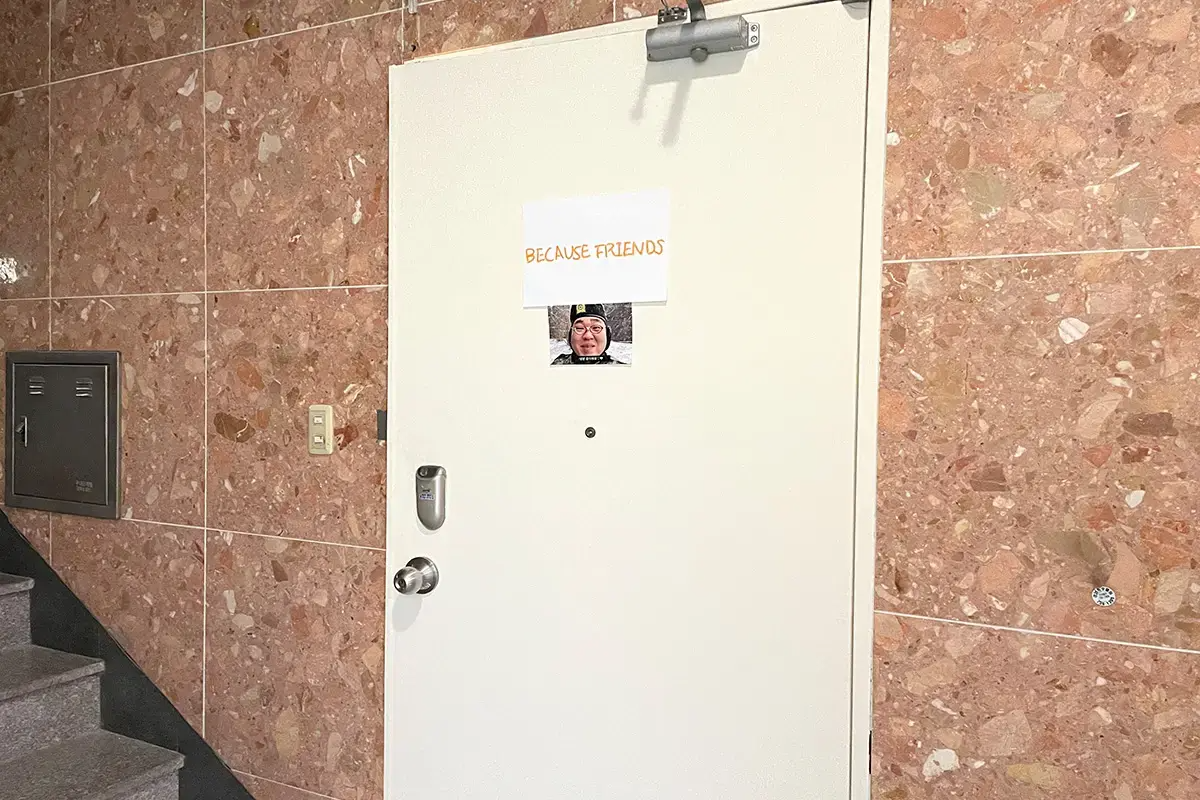 Entrance to Because Friends photo studio with a white door and a simple sign.