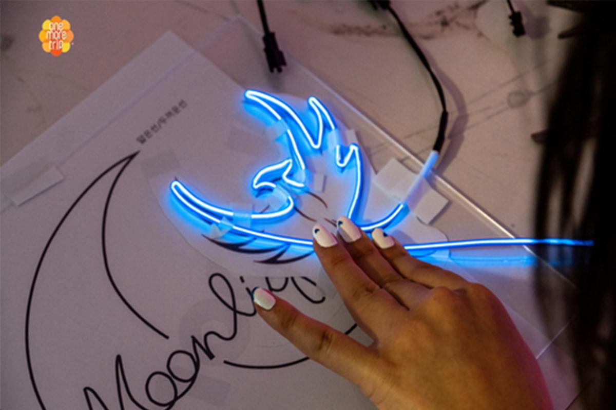 Pemula membuat desain neon sign menggunakan tabung neon biru di workshop SMOOD di Seoul.