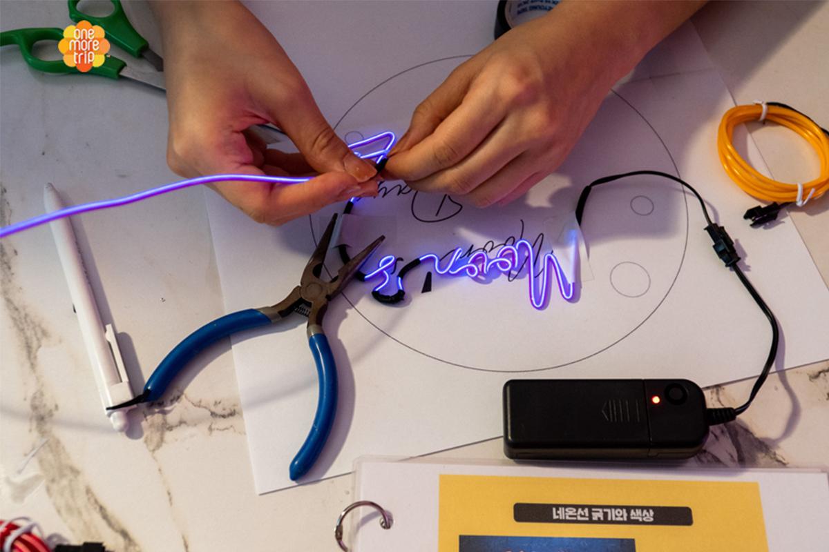 Peserta workshop SMOOD menekuk tabung neon dengan hati-hati saat merancang neon sign di Seoul, Korea Selatan.