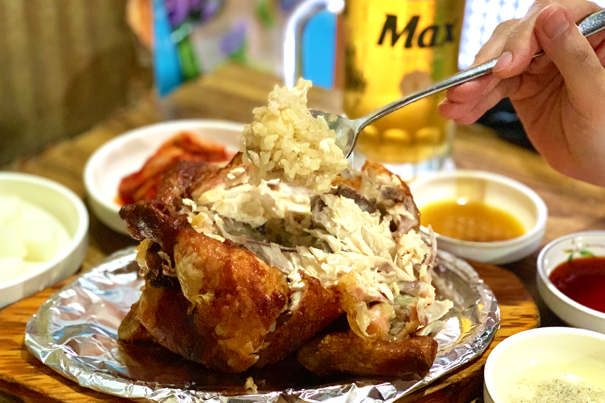 汉南洞汉方烤鸡配着泡菜和大米的特写镜头，展示其口感丰富的美食体验