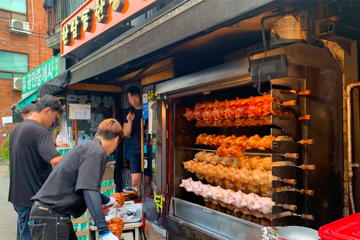 汉南洞汉方烤鸡店的外观和店前排队的顾客，显示该店的受欢迎程度