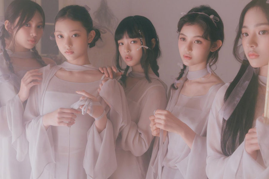 New Jeans身着雪纺芭蕾舞服，展现Ballet-core时尚，背景为朦胧粉色布景。