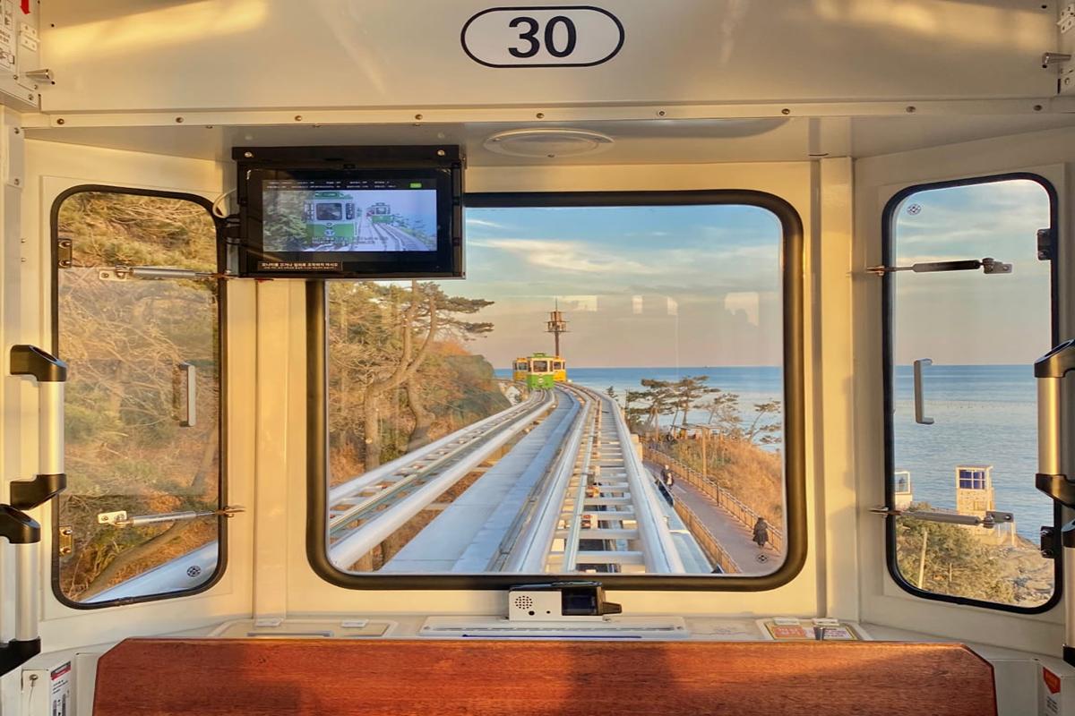 Захватывающий вид изнутри капсулы неба на железную дорогу и береговую линию с морским горизонтом.