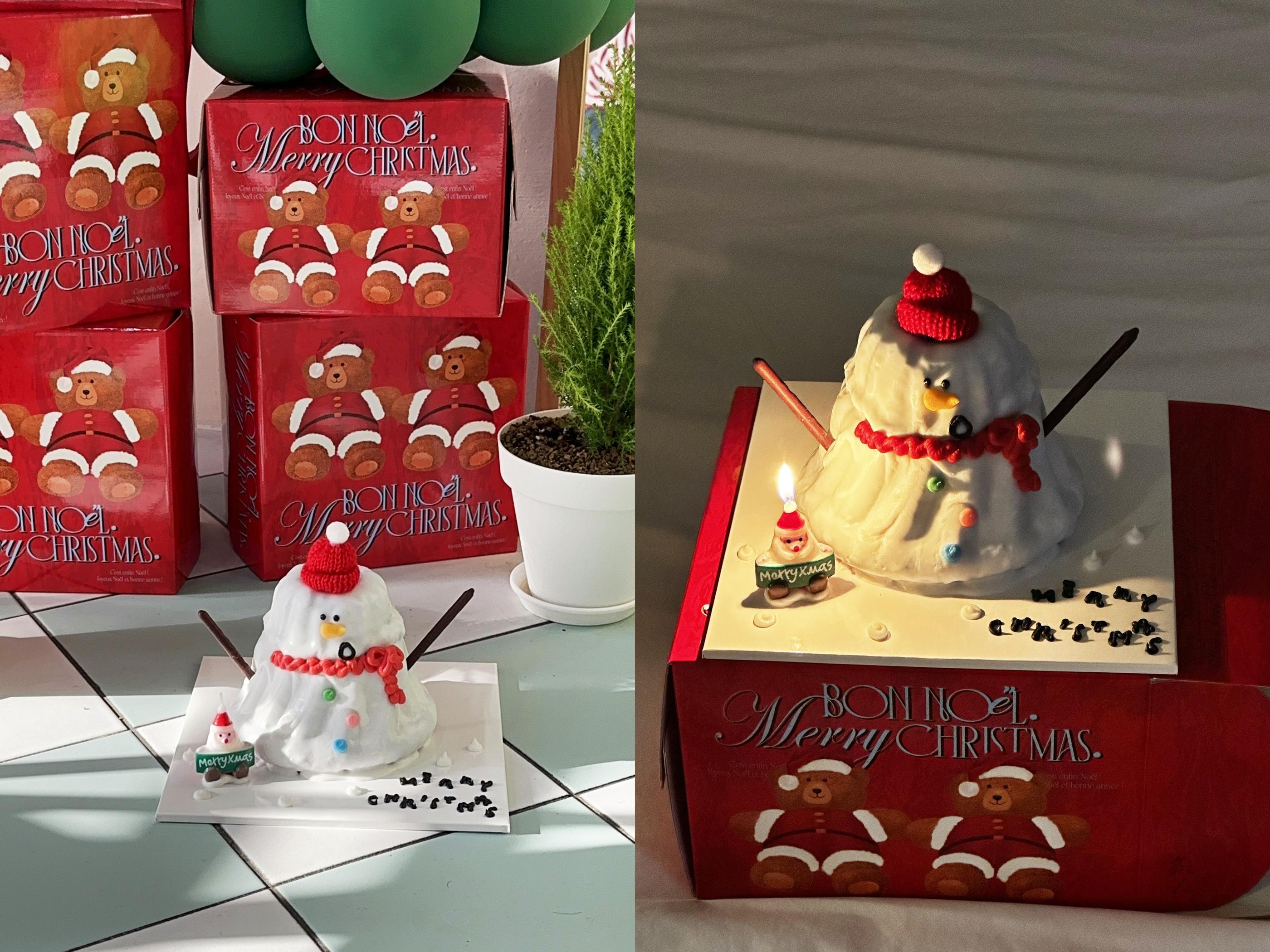 Gâteau bonhomme de neige blanc d'Ours Coffee à Jeju, avec bonnet et écharpe rouges, entouré d'emballages rouges de Noël.