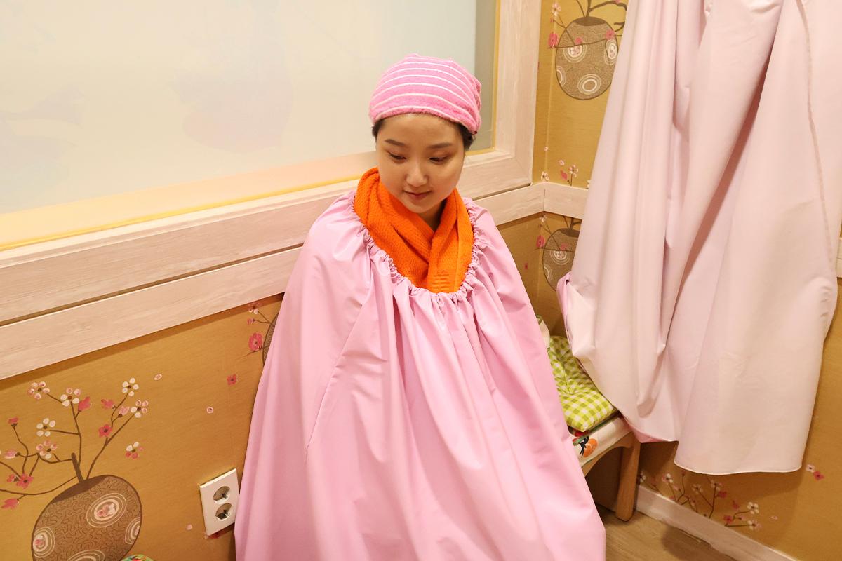 穿著坐薰服裝體驗韓國汗蒸幕上的蒸薰服務。