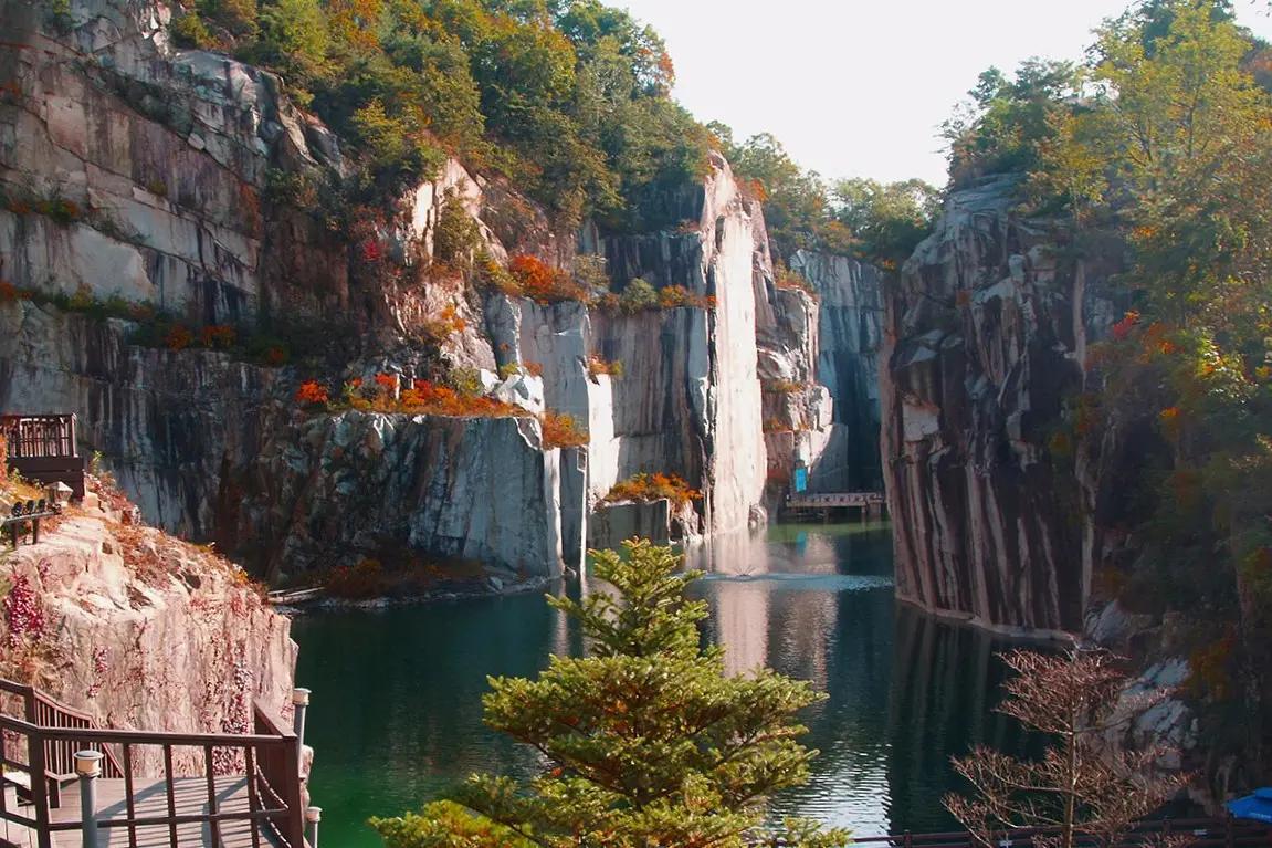 Tebing granit yang menjulang tinggi dengan air terjun di Pocheon Art Valley pada musim gugur dengan dedaunan berwarna-warni.