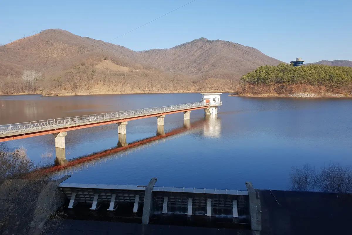 마장 호수 위에 자리잡은 다리와 주변 산들, 푸른 물결의 평화로운 풍경