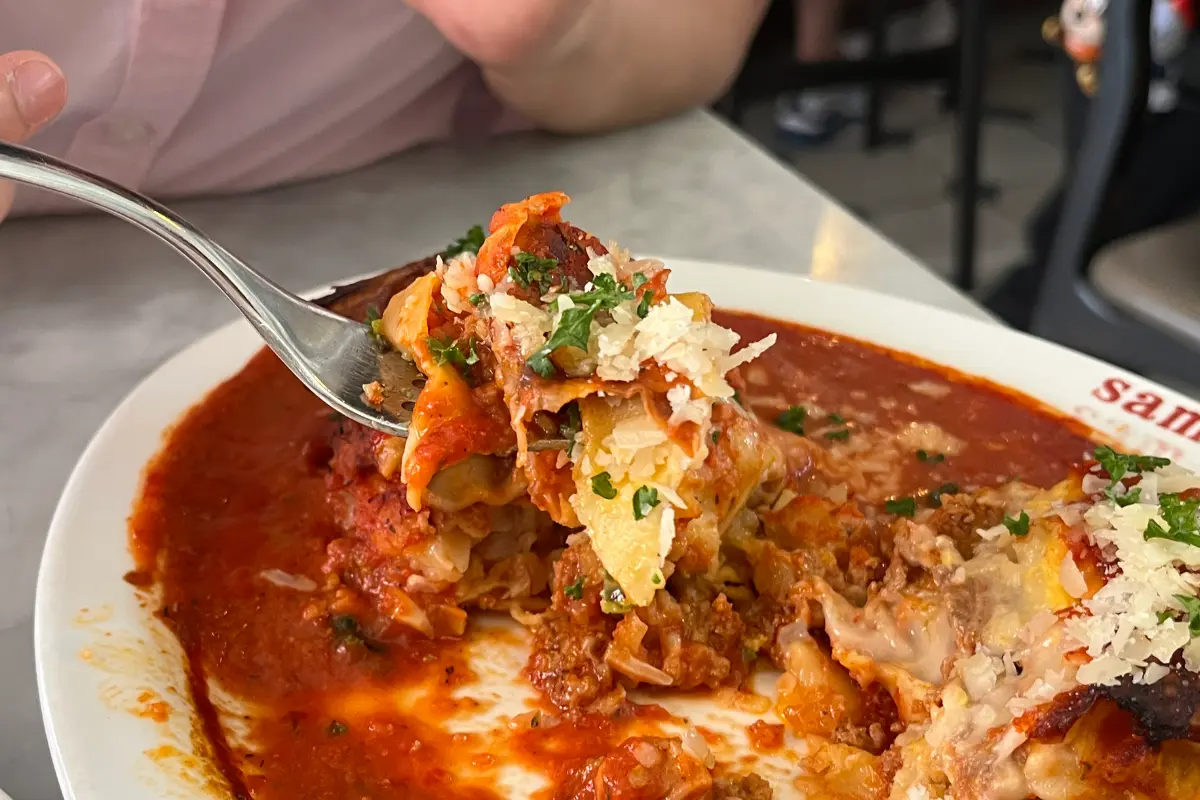 Nahaufnahme eines Stücks Lasagne, das mit einer Gabel aufgenommen wird, im Sam Sam Sam Restaurant.