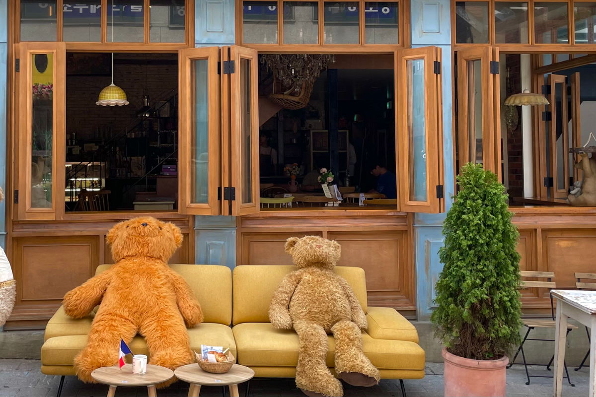 Sitzbereich im Freien des Teddy Beurre House Cafés, ideal für Fotos mit großen, niedlichen Teddybären.