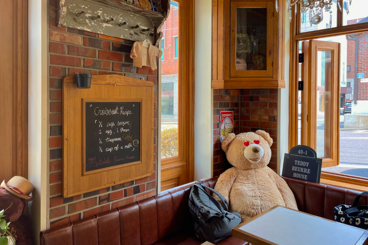 Gemütliche Sitzecke im Teddy Beurre House Café mit einem übergroßen Teddybär und Tafeldekoration.