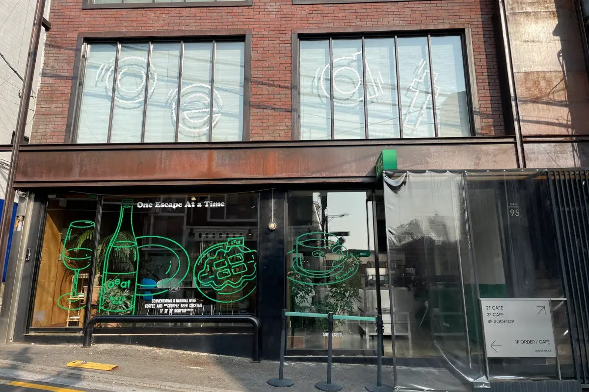 Außenansicht des Café Oeat in Haebangchon, Seoul, mit Retro-Schriftzug und farbigen Wandmalereien.