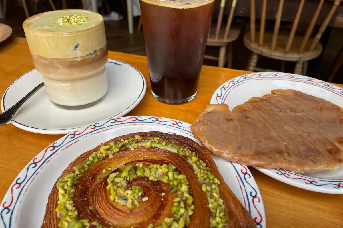 Köstlicher Pistazien-Kouign-amann auf einem Teller mit Getränken im Teddy Beurre House Café.