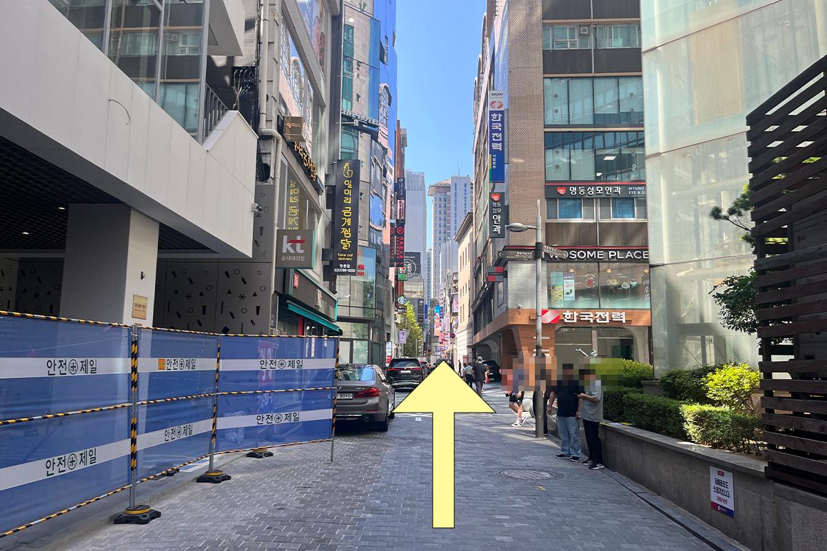 Walking path in Myeongdong, Seoul, showing the direction towards SD Store amidst urban scenery.
