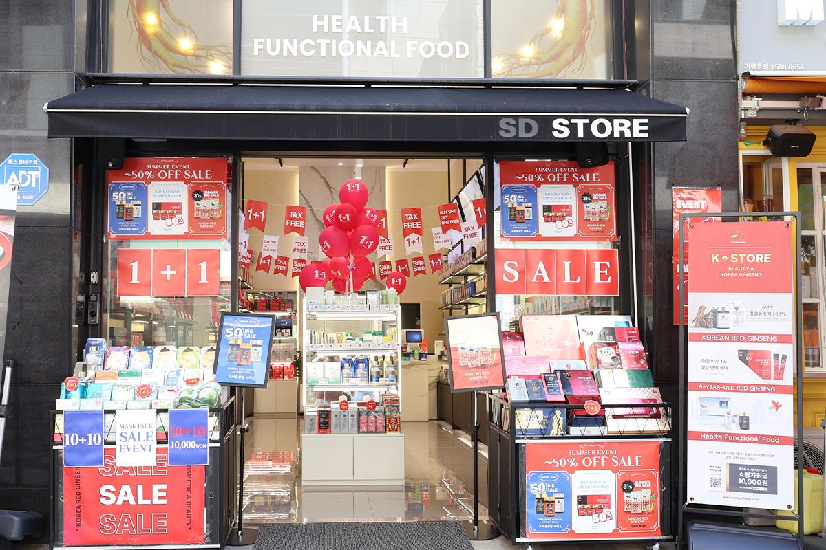 Exterior view of SD Store in Myeongdong with sale and promotional banners, showcasing Korean beauty and ginseng products on display.