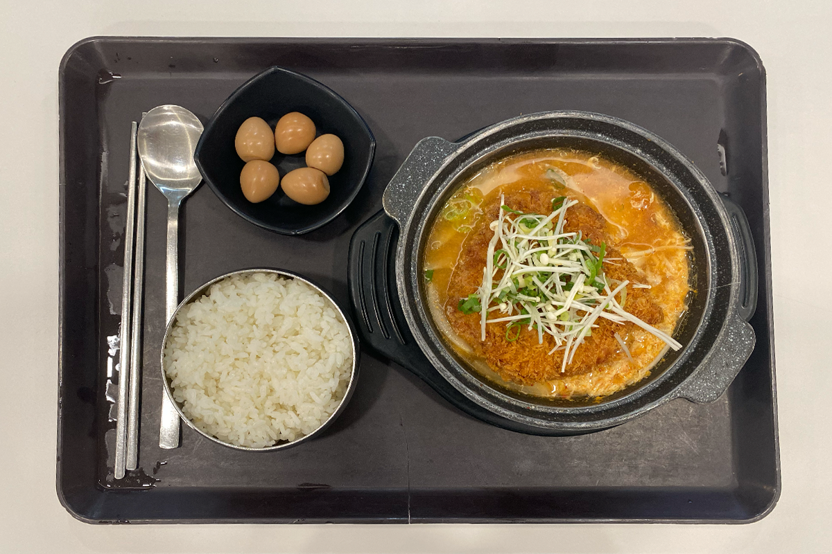 食堂のトレーに載せられたトンカツキムチ鍋定食セット