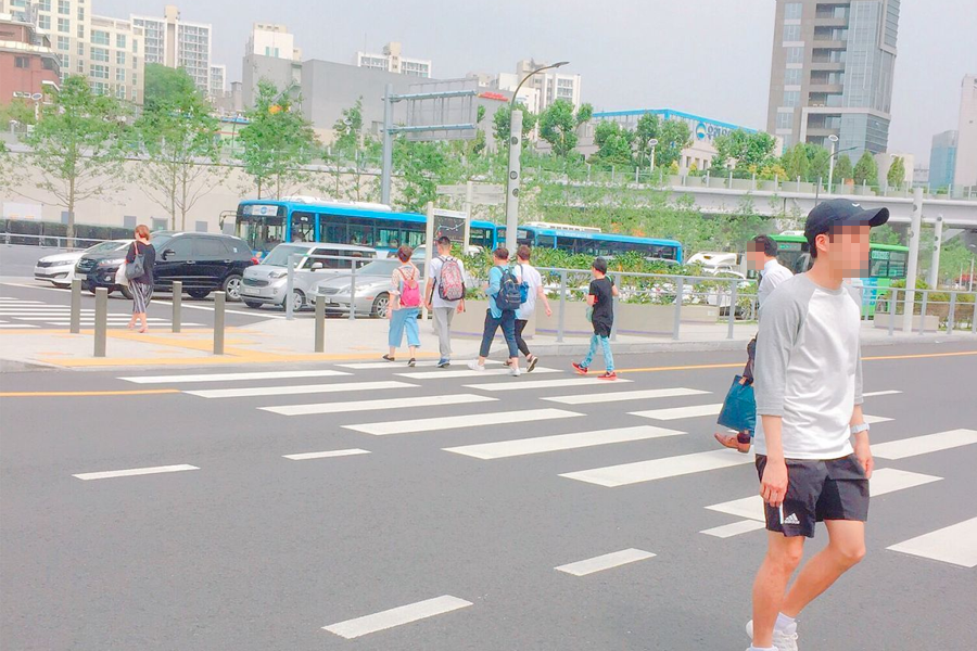 People crossing a street near Seoullo 7017 in Seoul, showcasing city life's vibrant energy.