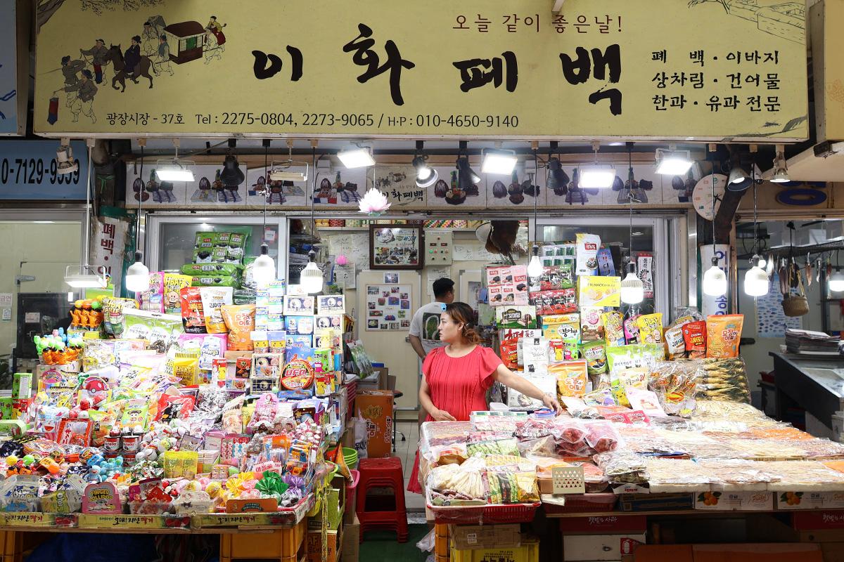 Esposizione di frutta secca e snack presso Ewha Sanghoe nel Mercato di Gwangjang, Corea, mostrando la vasta selezione disponibile per gli acquirenti.