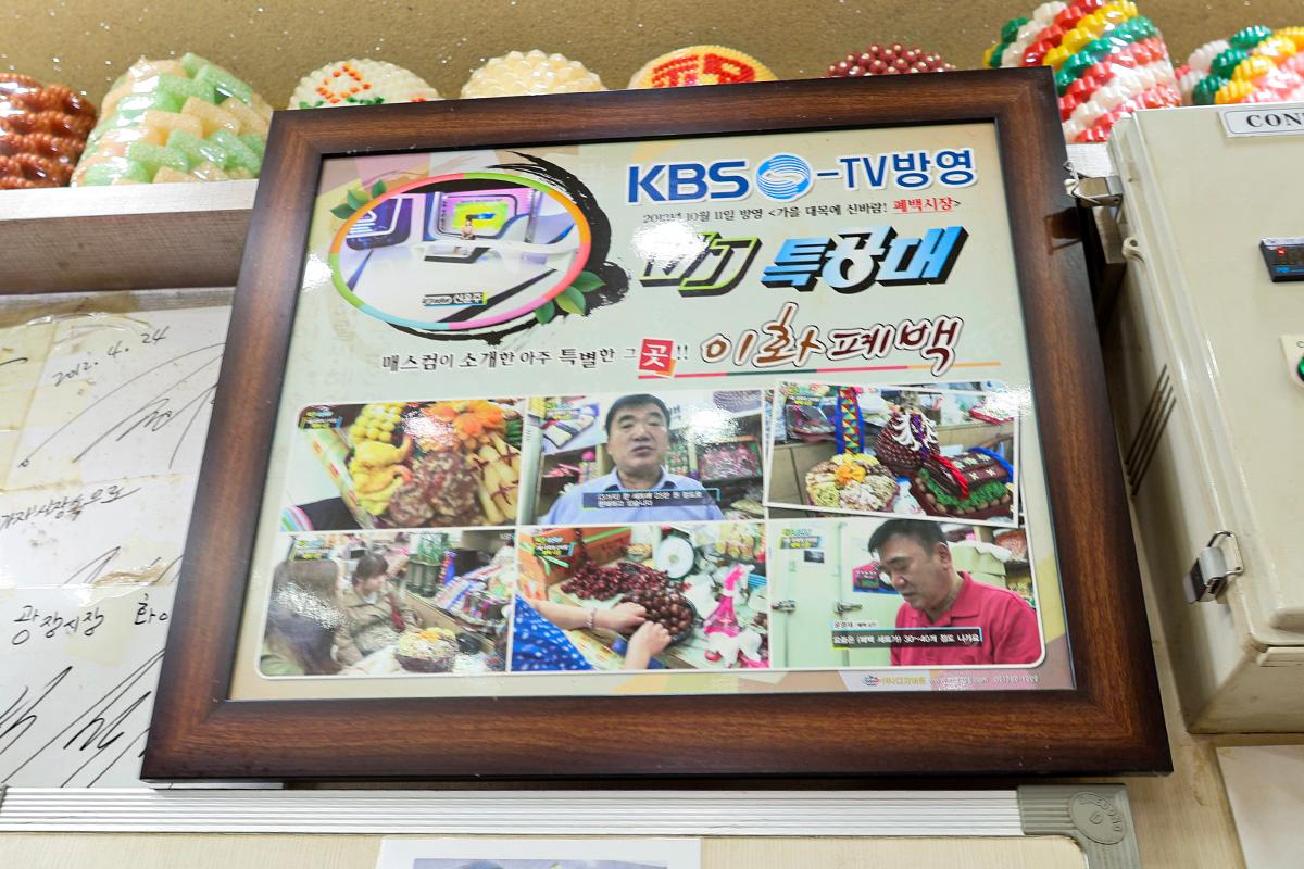 Cornice con foto di apparizioni televisive del negozio Ewha nel Mercato di Gwangjang, dimostrando la sua notorietà.