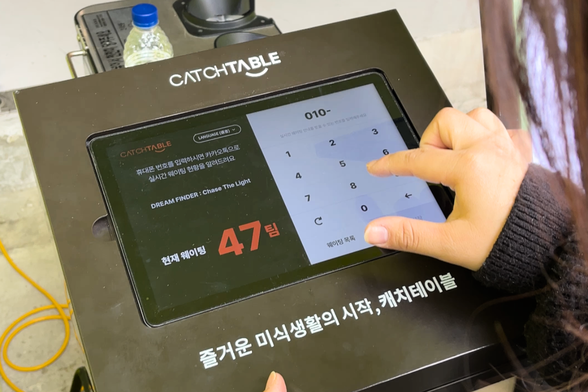 Hands interacting with a tablet system called CATCHTABLE for pop-up registration.
