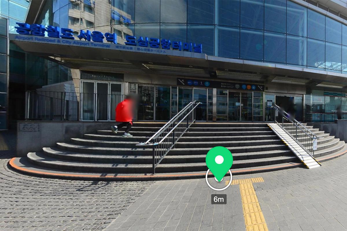 Сөүль галт тэрэгний буудлын орцны зураг. Гаднах талын харагдац нь лестницээр хөтөлж буй хүн, гадаа зогсож буй машин хамгийн зүүн талд байрлах.