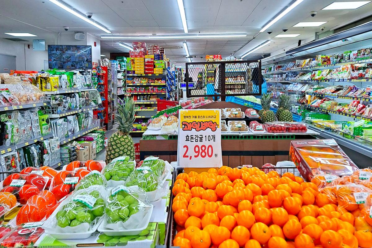 Fresh fruits including persimmons and grapes neatly arranged inside Hongdae Mart 24 Hours.