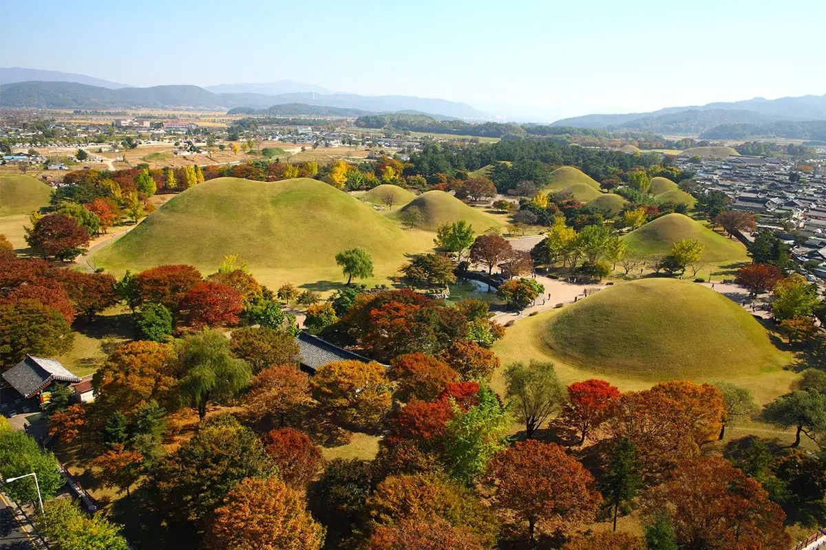 Wide aerial view of Gyeongju with Daereungwon tombs and surrounding fall scenery.