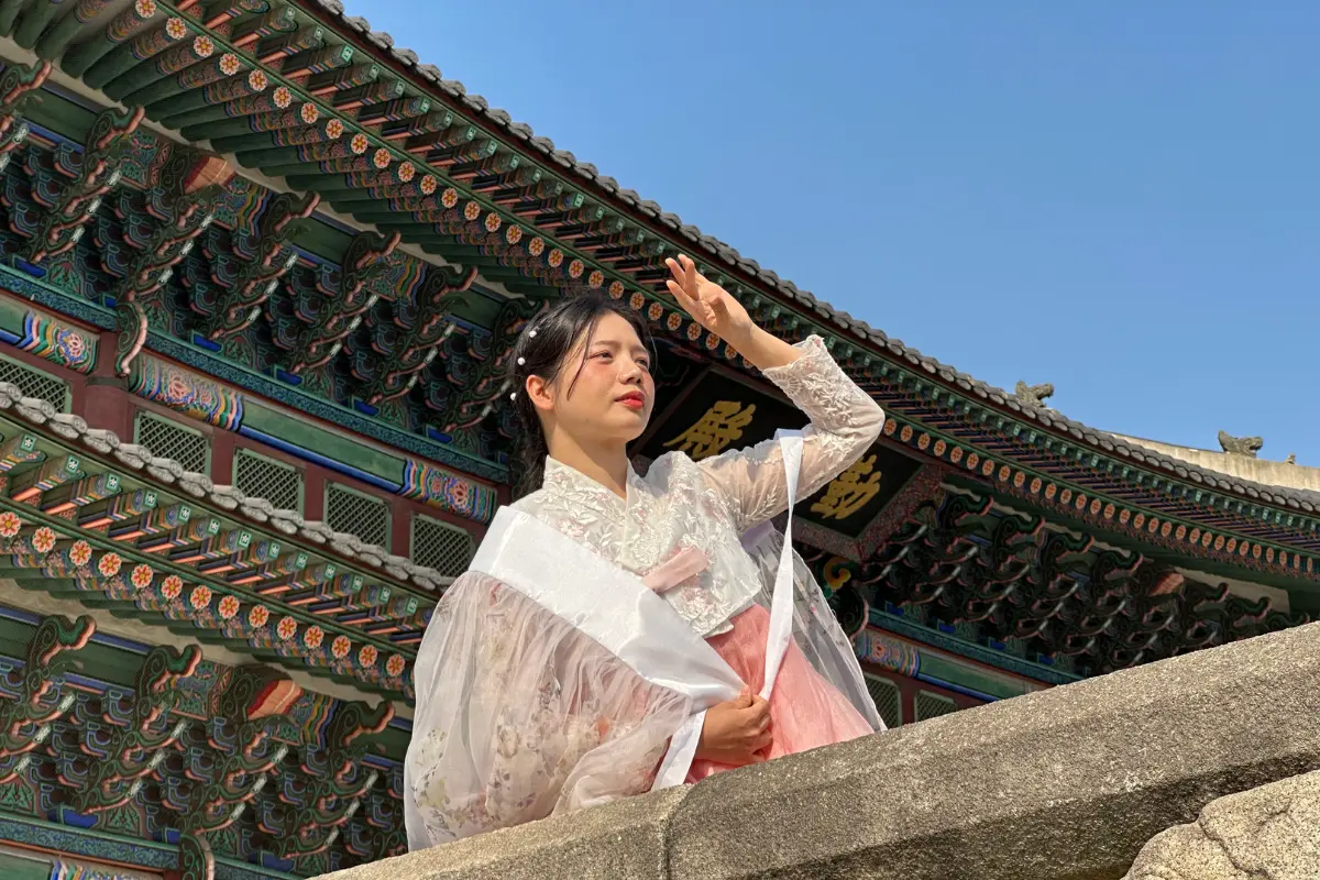 Người mặc hanbok đứng trên cầu thang Gyeongbokgung vào một ngày trời trong xanh tại Hàn Quốc