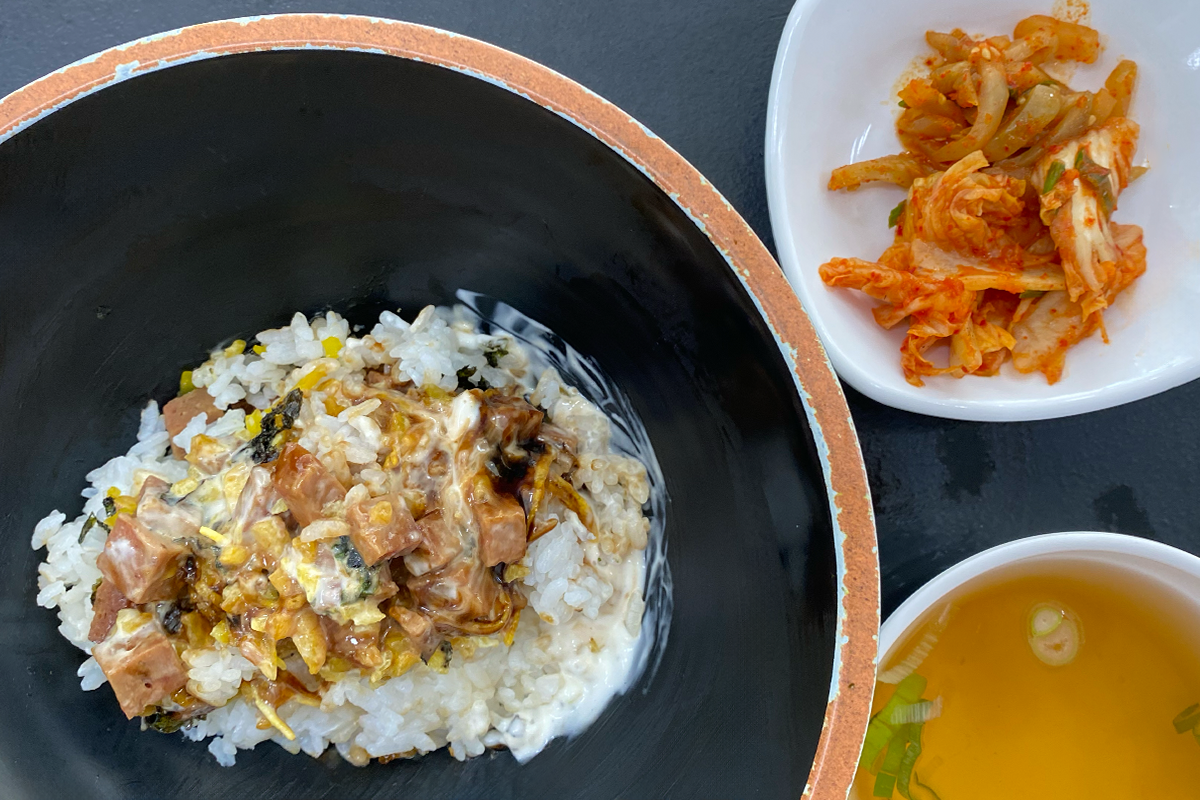 一碗火腿美乃滋盖饭，旁边配有泡菜和汤，展示美味的学生餐点。