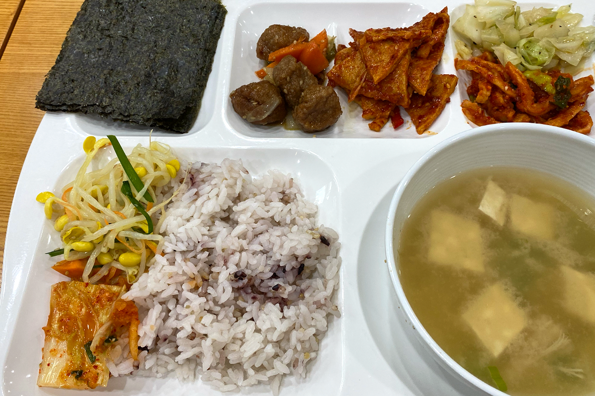 空的餐盘堆放在食堂中的取餐区，供学生使用。