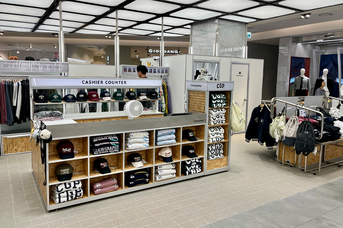 Code:graphy實體店的內部陳列，櫃臺上擺滿了品牌帽子和衣物，店內裝潢現代且整齊。
