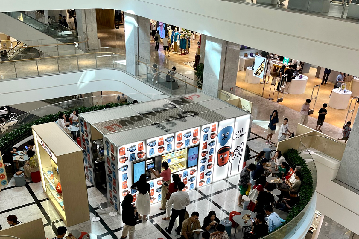 現代百貨內部場景，顧客正在一個小型咖啡店前選購飲品，商場設計時尚。
