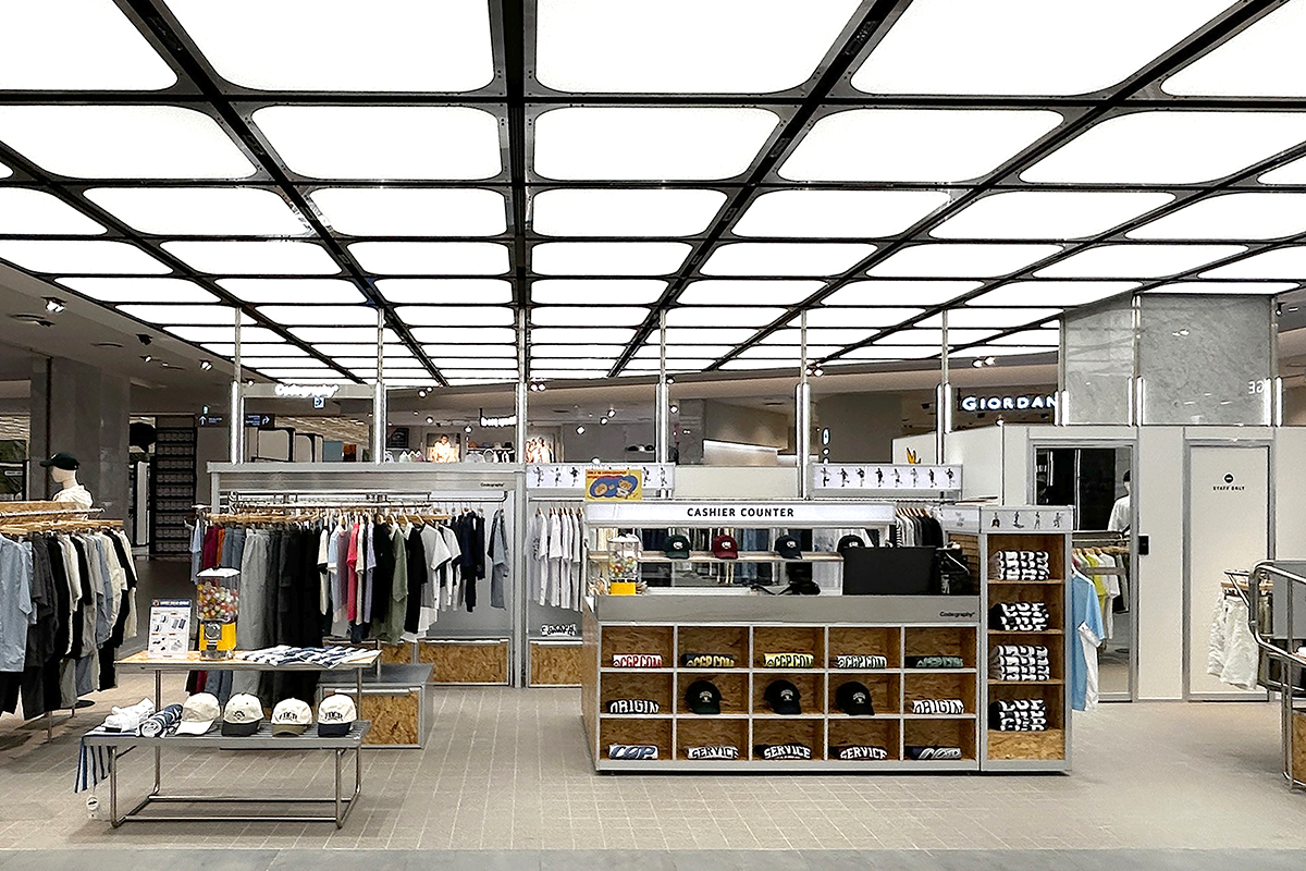 Code:graphy品牌的展示櫃，架上排列著各種服飾，包括帽子和T恤，充滿現代感和活力。