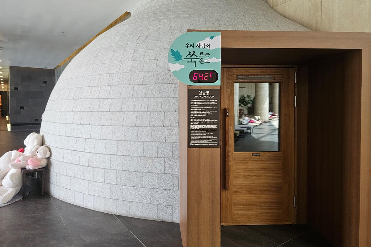 Entrance to a jjimjilbang charcoal room with temperature displayed, offering a unique sauna experience.