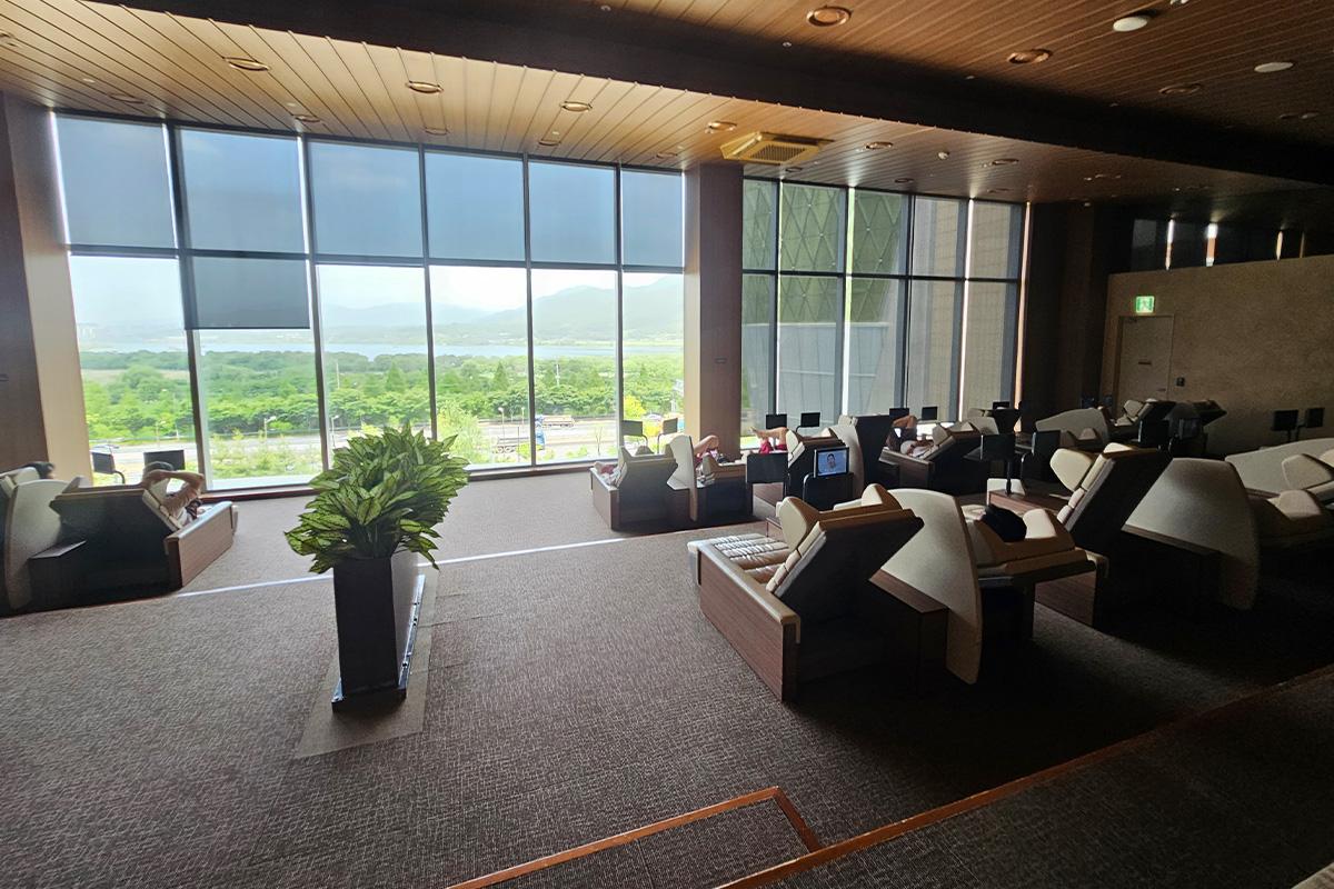 Expansive seating area with panoramic views at a Korean sauna relaxation zone overlooking greenery.