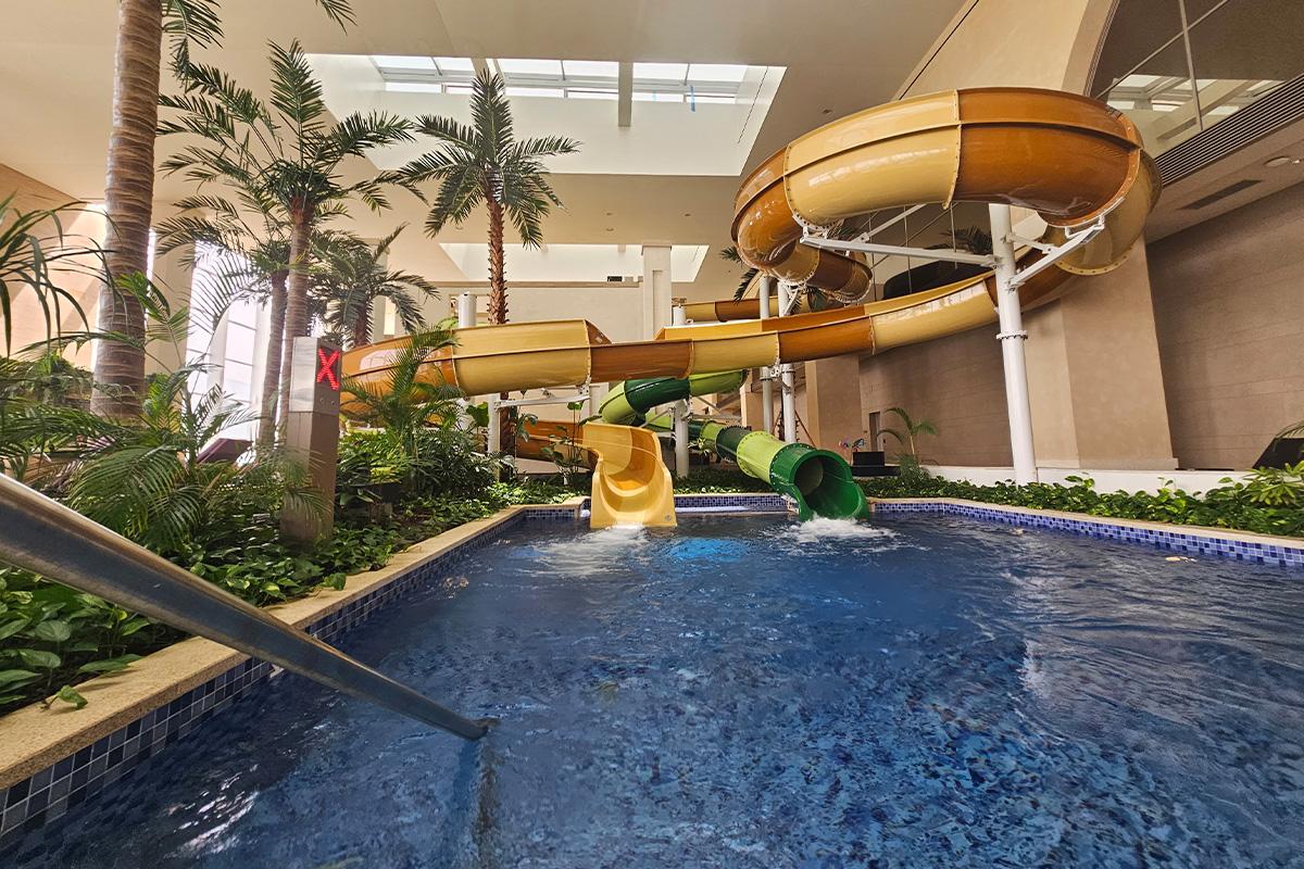 Green and yellow water slides in Aqua Field indoor water park for a thrilling ride