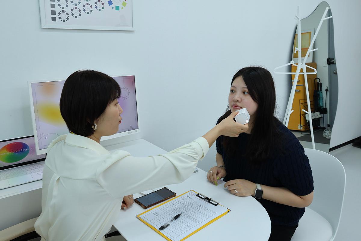 Consultant using a device to measure skin tone during personal color consultation at Vivid Kang.