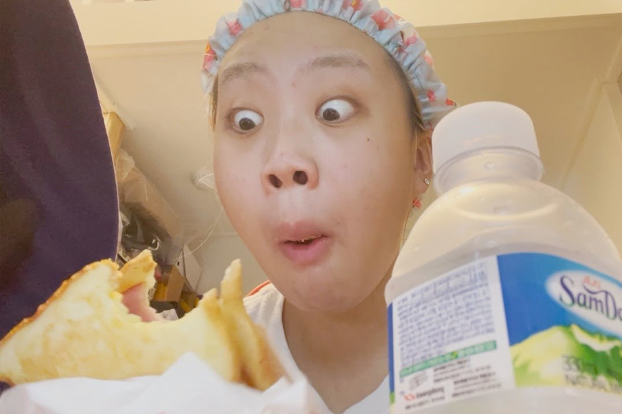 李泳知在享用一份高热量的食物，她正在吃三明治，并搭配一瓶矿泉水，展示她在减肥过程中没有严格限制饮食。