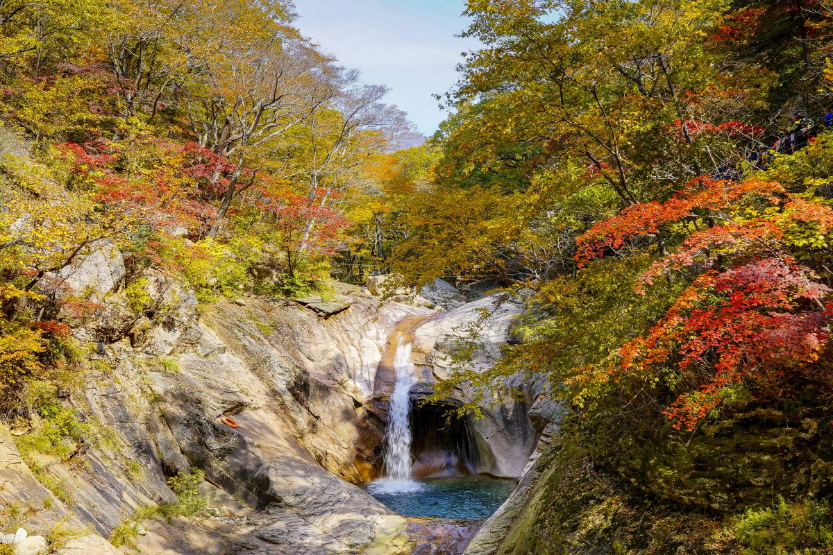 Seoraksan Mountain, South Korea, showcasing stunning autumn foliage and a tranquil waterfall.