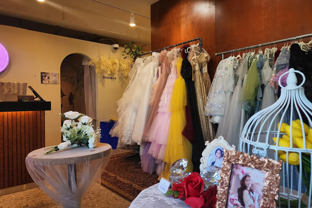 新村LAFIA Studio內一排色彩繽紛的禮服懸掛在展示架上,前方有花籃裝飾