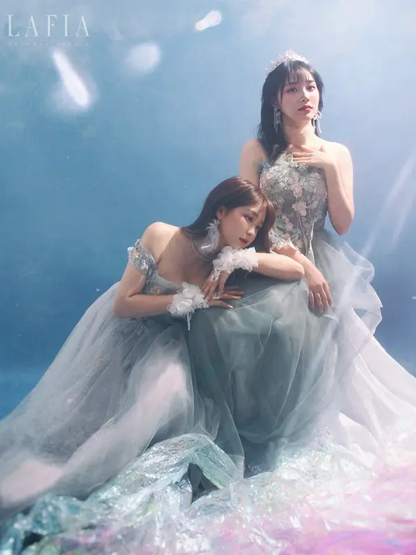 兩名女子穿著高雅花紋禮服在水下藍色背景前拍攝創意照片