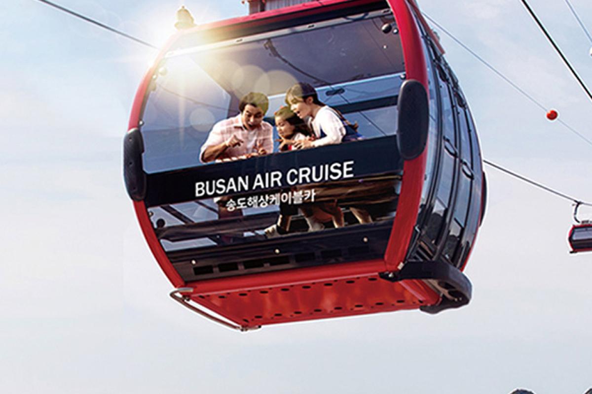 Vue extérieure de la cabine du téléphérique Songdo Air Cruise à Busan, flottant au-dessus de la mer avec des passagers à l'intérieur.
