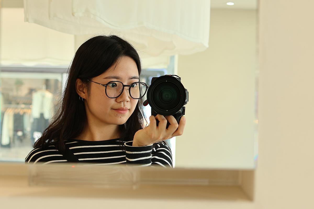 Person using a mirror to check how they look in eyeglasses at VIEWMAP.